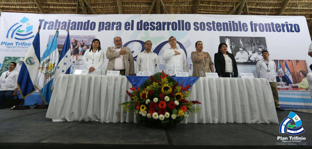 El Vicepresidente de la República de Guatemala, Jafeth Cabrera; el Vicepresidente de la República de El Salvador, Óscar Ortíz y la Designada Presidencial de la República de Honduras, Rossana Guevara durante su visita a la Región Trifinio, específicamente al municipio de Esquipulas, Chiquimula, participaron en el acto de conmemoración de los treinta años del Plan Trifinio, además de la firma del convenio marco entre la Red de Mancomunidades y la Comisión Trinacional del Plan Trifinio -CTPT-. Durante el evento, estuvieron presentes Alcaldes Municipales que forman parte de la región, representantes de los gobiernos departamentales, Ministerios nacionales de los tres países, representantes de la cooperación Internacional, Mancomunidades de la Región Trifinio y los miembros de la Secretaría Ejecutiva Trinacional. Antecedentes del Plan Trifinio  El Plan Trifinio, nace el 12 de noviembre de 1986 con la suscripción del  Acuerdo de Cooperación Técnica de los Gobiernos de las Repúblicas de Guatemala, Honduras y El Salvador con la Secretaría General de la Organización de los Estados Americanos (OEA) y el Instituto Interamericano de Cooperación para la Agricultura (IICA) para la formulación de un Plan de Desarrollo en la Región Fronteriza de los tres países” cuyo financiamiento provenía de las cinco partes que suscribieron el Acuerdo y de la Comunidad Económica Europea. En el año de 1997, se firma el Tratado entre las Repúblicas de El Salvador, Guatemala y Honduras para la ejecución del Plan Trifinio y se institucionaliza a la Comisión Trinacional del Plan Trifinio (CTPT), integrada por los Vicepresidentes de El Salvador y Guatemala y una Designada (o) de la Presidencia de Honduras. El Tratado tiene como objetivo el fortalecimiento institucional del Plan Trifinio; además delimita el espacio geográfico de intervención, define las competencias de la CTPT y de sus instancias permanentes para la ejecución del mismo.  Reconoce al territorio como “una unidad ecológica indivisible”, en la que solo la acción conjunta de los tres gobiernos podrá dar solución satisfactoria a la problemática de la población del área y al manejo sostenible de sus recursos naturales. Conmemoración de los treinta años del Plan Trifinio En el acto de conmemoración de los treinta años del Plan Trifinio se dieron a conocer los avances y principales logros durante todos estos años que la institución ha alcanzado, los cuales han sido posible gracias al liderazgo de los miembros de la CTPT, a la colaboración de las instituciones nacionales de los tres países, a los Alcaldes y Mancomunidades, a la cooperación internacional, las redes y plataformas conformadas a nivel trinacional, a las ONG´s presentes en el territorio y a las comunidades de la Región Trifinio.  Logros y avances del Plan Trifinio en sus 30 años •	Se ha realizado una inversión goblal de 131.9 millones de dólares, 124 millones provenientes de la cooperación internacional y 7.9 millones de los gobiernos de los tres países, con los cuales se ha fortalecido el proceso de integración trinacional, la cooperación transfronteriza, se han hecho importantes aportes para el desarrollo una economía sustentable agrícola y no agrícola; se ha promovido una gestión integrada de los recursos hídricos y un mejor manejo de los recursos naturales, así como obras para la mitigación y adaptación al cambio climático.  •	Se ha incrementado la conservación de la biodiversidad en las 13 áreas protegidas con las que cuenta la región, y se ha trabajado estrechamente con los Ministerios de Medio Ambiente de los tres países con este propósito.  La presencia de escarabajos de la familia Curculionidos en la reserva de Montecristo, es parte de la evidencia de ello.  •	Se han realizado mejoras en la fertilidad de los suelos, en la disminución de la erosión y aumento en la infiltración de agua con la implementación de sistemas agroforestales con café, frutales y forestales.  •	A lo largo de su existencia, el Plan Trifinio, ha logrado atender 25 mil hectáreas de tierra a través de incentivos, obras de conservación de suelos y agroforesteria, protección de fuentes de agua entre otros, que han impactado positivamente a la región.   •	Además, se han elaborado mecanismos de compensación financiera, “Fondo Verde”, a través de los cuales las comunidades rurales que se benefician de los recursos hídricos cuencas arriba, colaboran con la protección y conservación de los bosques.  •	25,000 familias rurales mejoraron sus medios de vida, su seguridad alimentaria, acceso al agua potable, infraestructura de saneamiento básico y han incrementado sus ingresos a través de la diversificación de su producción agropecuaria en forma sostenible, por medio de cultivos de café, frutales, hortalizas, granos básicos y ganadería, así como el desarrollo de sus actividades turísticas y artesanías, entre otros   •	En el rubro de ganadería, más de 3,791 hectáreas han aumentado la producción de leche con la implementación del enfoque de ganadería ambientalmente sostenible.  •	Se ha mejorado a su vez la infraestructura productiva, con más de 500 hectáreas de riego y más de 1,000 kilómetros de caminos vecinales que han permitido mejoras en las condiciones para la producción agropecuaria y rural.  •	19 mil personas han sido beneficiadas con la construcción de 85 obras de mitigación al cambio climático, ejecutadas en conjunto con las municipalidades de la región.  •	Se han construido 68 beneficios ecológicos de café y se ha dotado de equipos para el procesamiento básico de alimentos y la construcción de reservorios de agua a asociaciones de productores y comunidades rurales  •	2,000 micro y pequeños empresarios y emprendedores rurales han fortalecido sus capacidades productivas de mercadeo y acceso a financiamiento a través de cajas de crédito.  •	Se definió en conjunto con la Cámara Trinacional de turismo Sostenible y en consulta con los Ministerios de Turismo de los tres países, quienes son miembros del Comité Interinstitucional de Turismo Sostenible de la región Trifinio, la Ruta Trinacional de Turismo Sostenible, con siete polos geográficos con sus respectivos destinos y productos turísticos.  •	Se ha apoyado la elaboración de políticas públicas locales y ordenanzas municipales para un mejor ordenamiento y desarrollo territorial de la Región Trifinio; y se han creado Oficinas de Planificación y Gestión Territorial (OPLAGEST) en El Salvador y que se espera extender a los otros países.  •	Así mismo, se han implementado diferentes procesos de formación de capacidades a técnicos de las unidades ambientales de las municipalidades, de instituciones nacionales, ONG y otras instancias locales y nacionales.   •	Uno de los más  grandes resultados de estos treinta años es la conformación de un capital de integración con la participación de múltiples actores de la región: la Red de Mancomunidades, la Cámara Trinacional de Turismo Sostenible, la Mesa Trinacional del Café, el Comité Trinacional de Áreas Protegidas, la RED de propietarios privados de áreas protegidas, el Grupo de Trabajo Local de la ECADERT,  quienes se han integrado en función de promover el desarrollo sostenible fronterizo de esta región en temas especiales, además del Comité Consultivo Trinacional creado por el Tratado del Plan Trifinio.